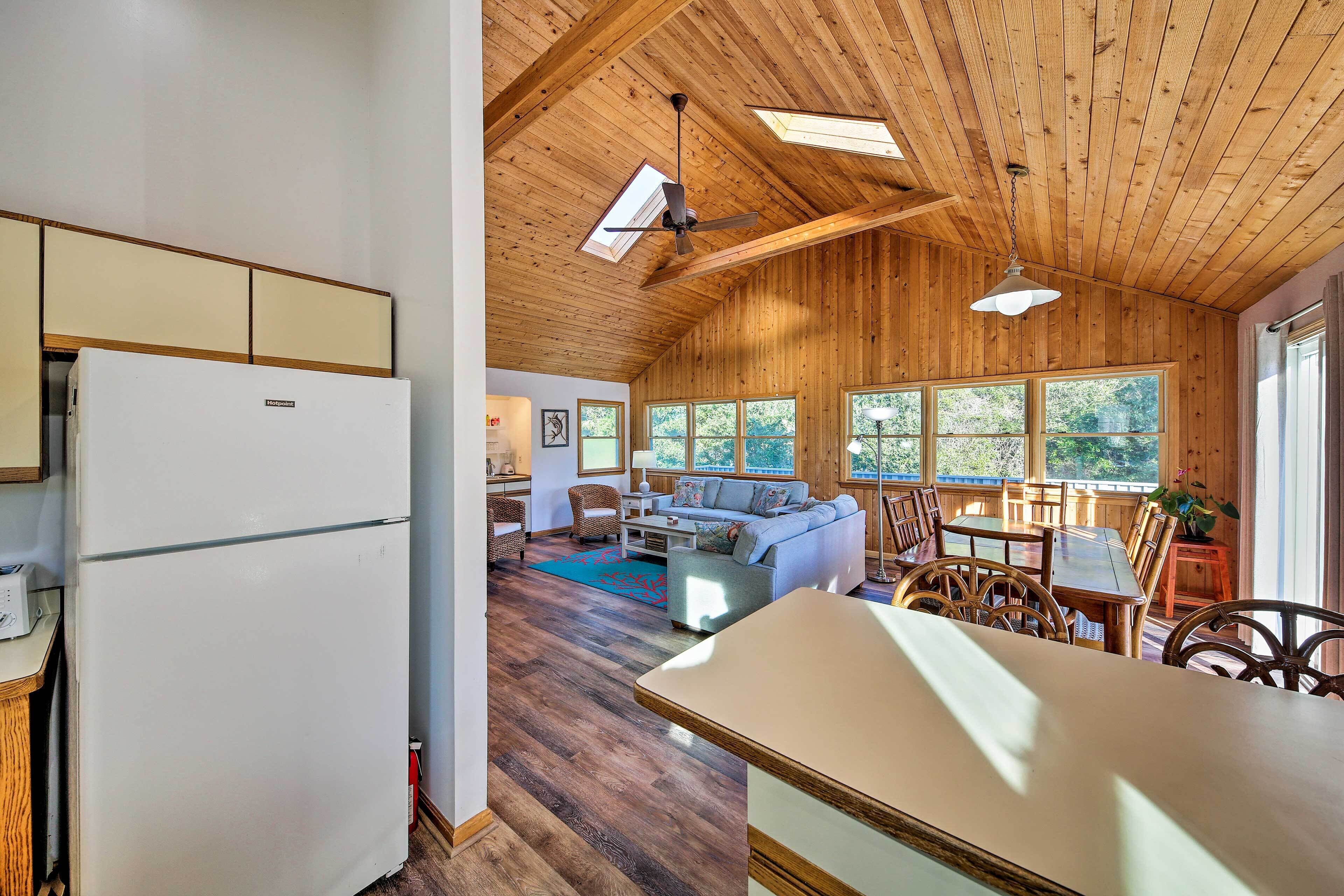 A spacious living area with a wooden ceiling, a large window, and a sofa.
