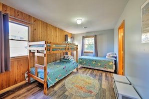A room with two bunk beds, a round rug, and a small table.
