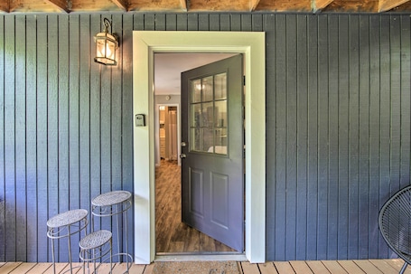 A wooden door with a glass panel, a metal lantern, and a small outdoor seating area with metal tables.