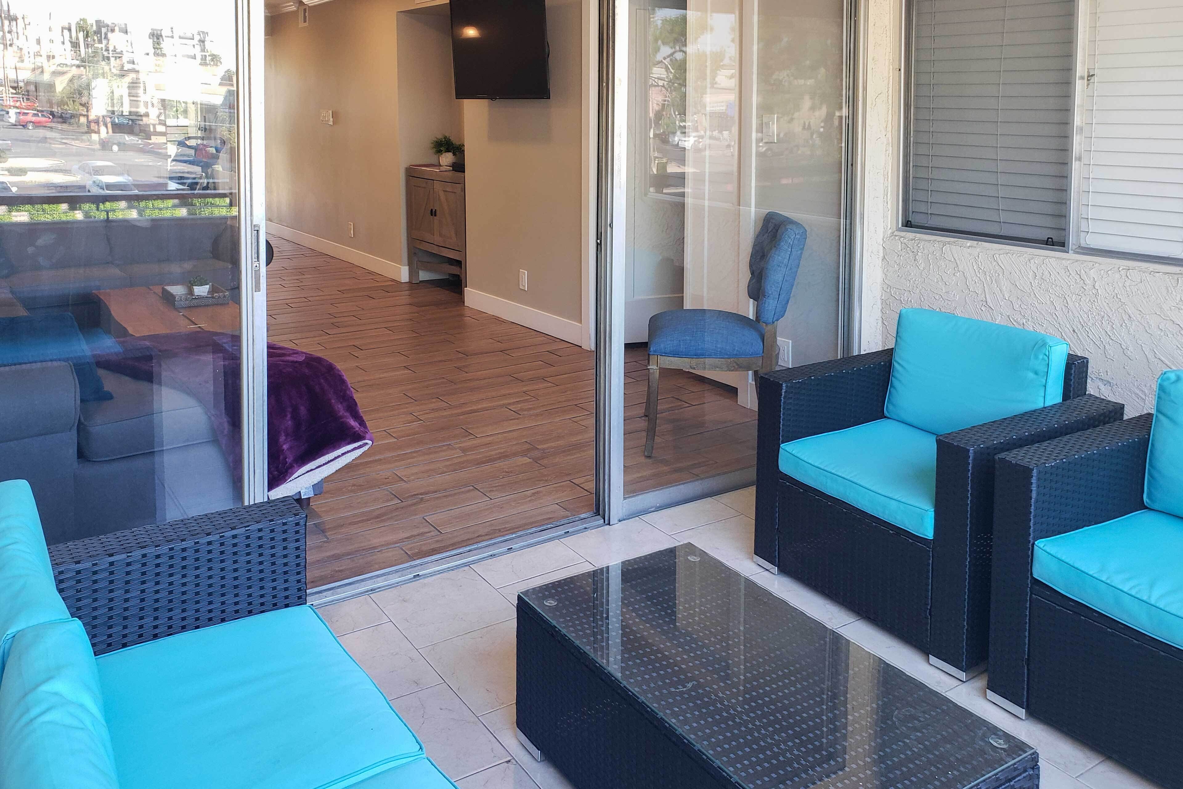 Un espacio al aire libre moderno con mobiliario de mimbre y una pared de vidrio.