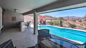 Zona de piscina con vistas a montañas, un bar y asientos al aire libre.