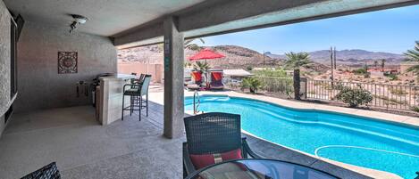 A pool area with a view of mountains, a bar, and outdoor seating.