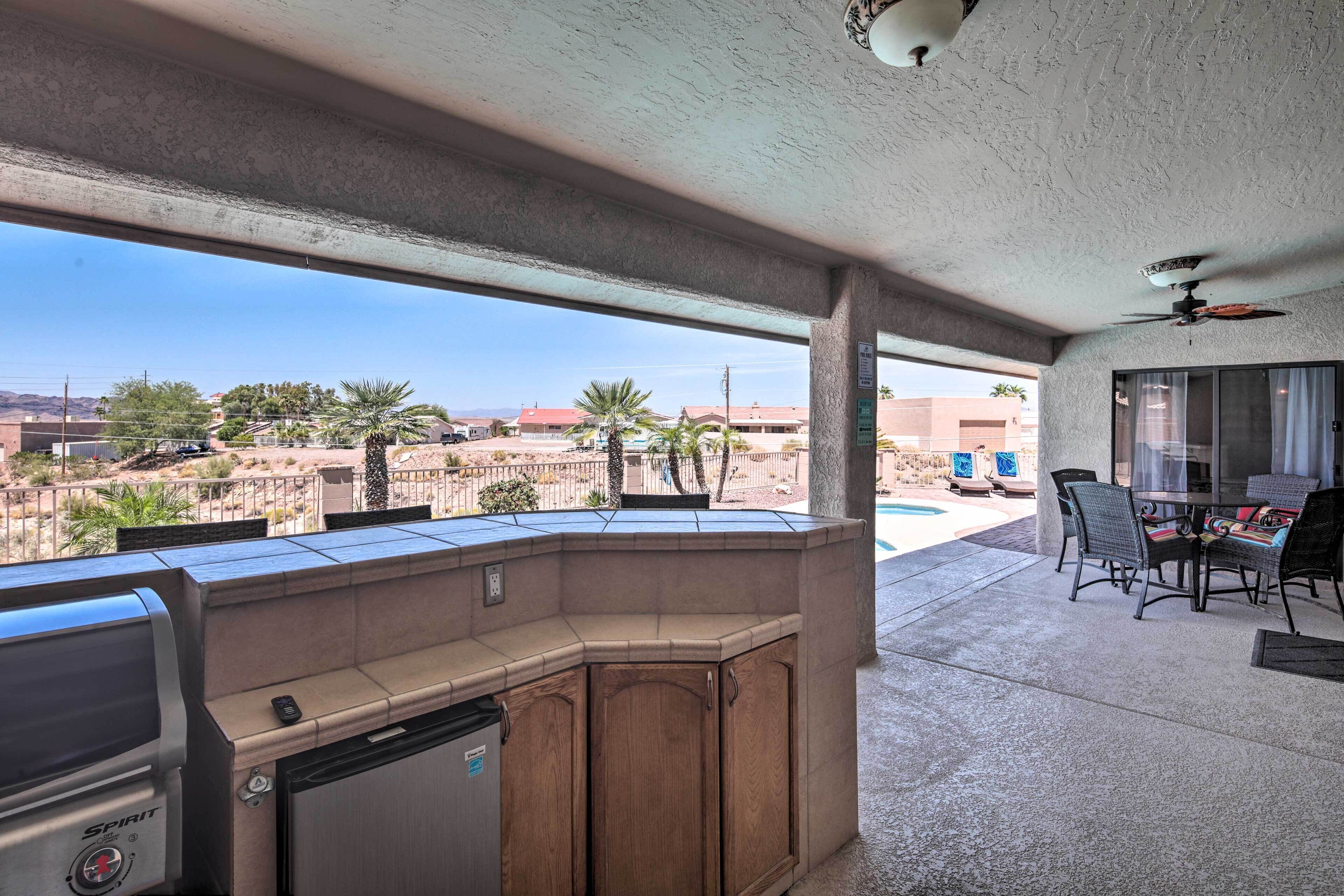 A patio with a grill, seating, and a view of a residential area.
