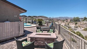 Un patio con mobiliario exterior, una piscina y vistas al paisaje desértico.