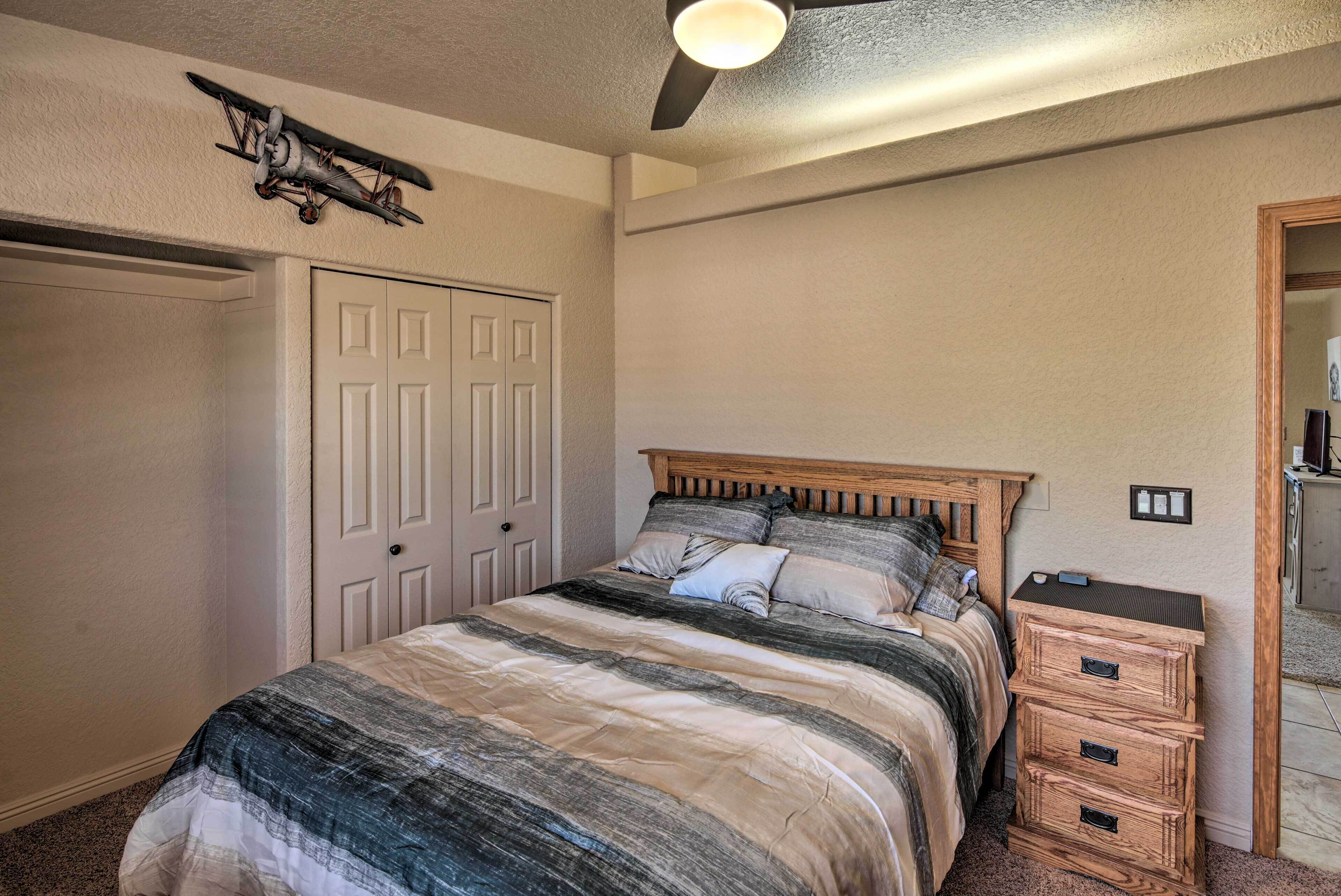 A bedroom with a bed, a ceiling fan, a wardrobe, and a nightstand.