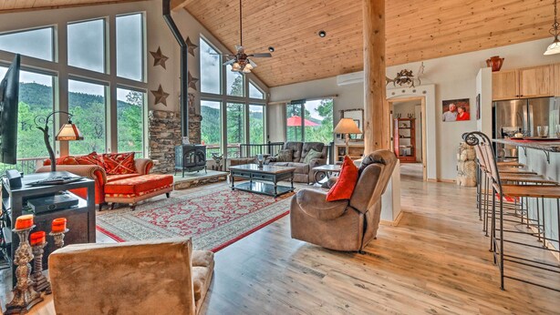 A spacious living area with a fireplace, large windows, and a high ceiling. - Fire Pit, Deck & Grill: Serene Prescott Cabin! (Prescott)