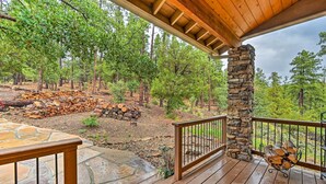 A wooden deck with stone flooring, a stone pillar, and a railing. - Fire Pit, Deck & Grill: Serene Prescott Cabin! (Prescott)