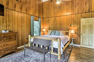 Un dormitorio con paneles de madera, una cama, lámparas de noche, un aparador y un banco.