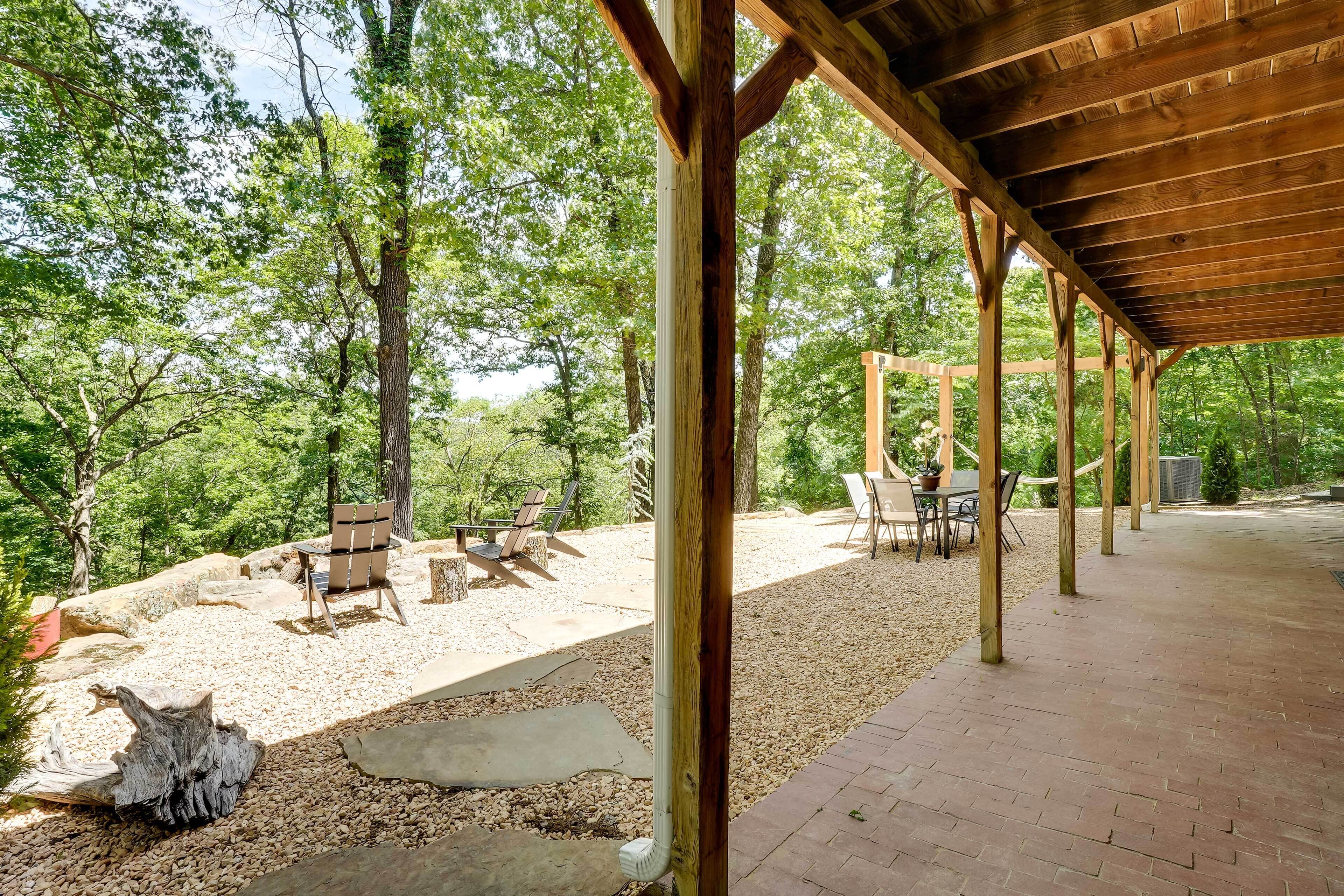 An outdoor patio area with wooden pergola, seating, and gravel ground.