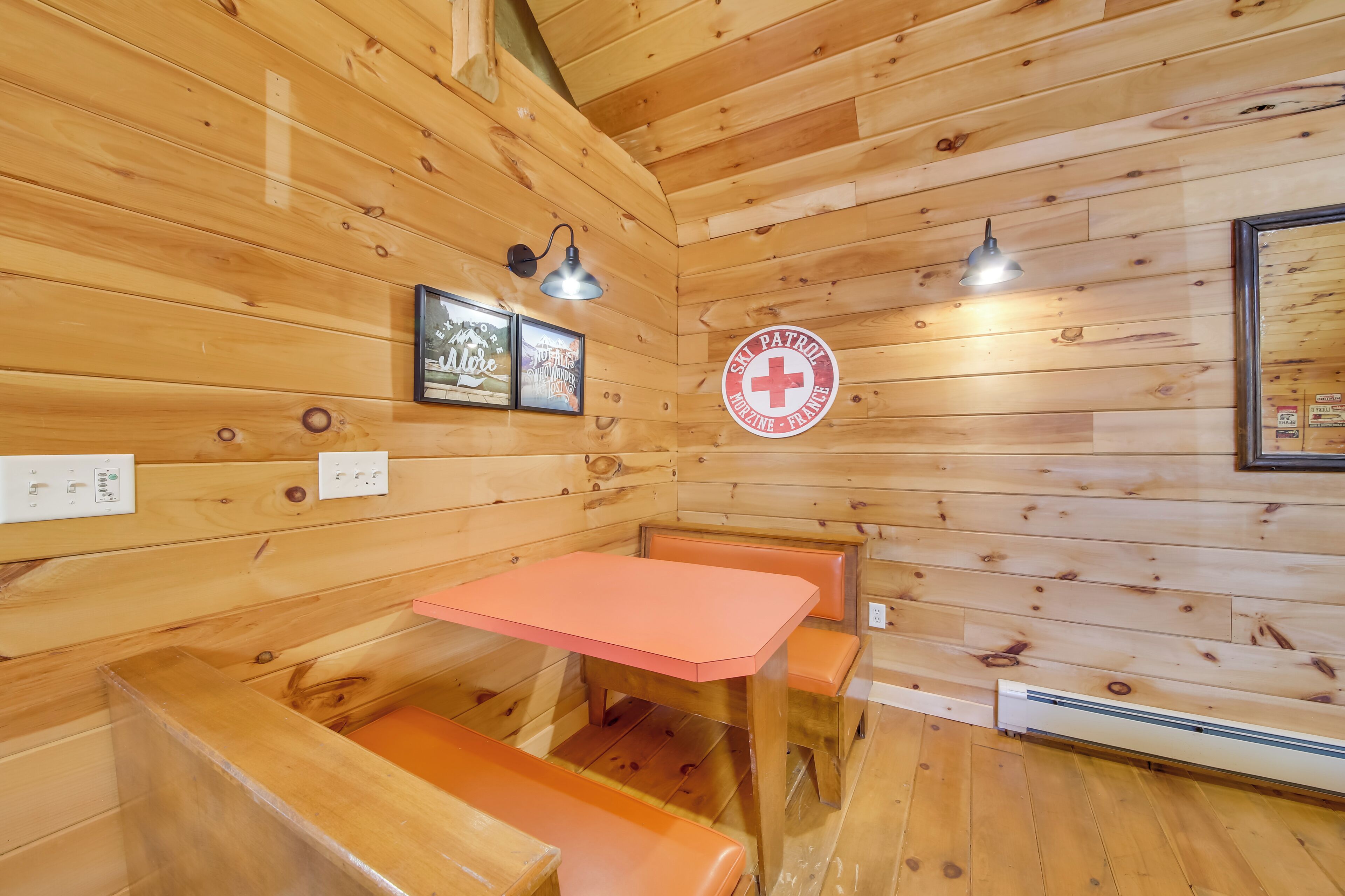 Ein Holzblockhaus-Interieur mit einem rosa Tisch und Bänken, gerahmten Bildern an den Wänden und einem Logo der Skiregierung.