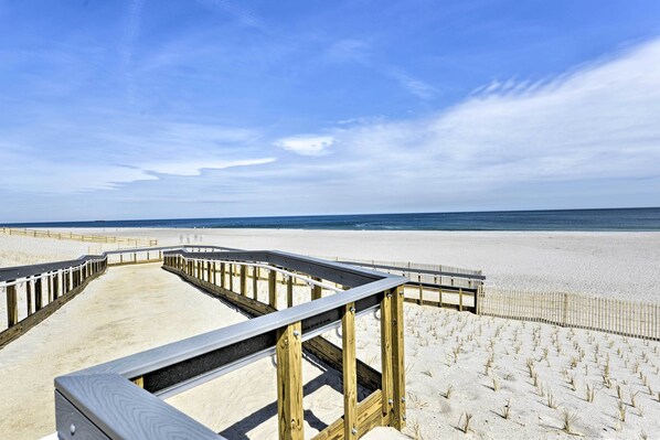 A wooden boardwalk leading to a sandy beach with a clear sky.