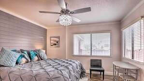 A bedroom with a tufted bed, a ceiling fan, a window with blinds, a chair, and a small table. - Pismo Beach Condo < Walk to Beach & Wineries! (Pismo Beach)