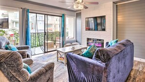 A spacious living room with a ceiling fan, a fireplace, and a large window overlooking a balcony. - Pismo Beach Condo < Walk to Beach & Wineries! (Pismo Beach)