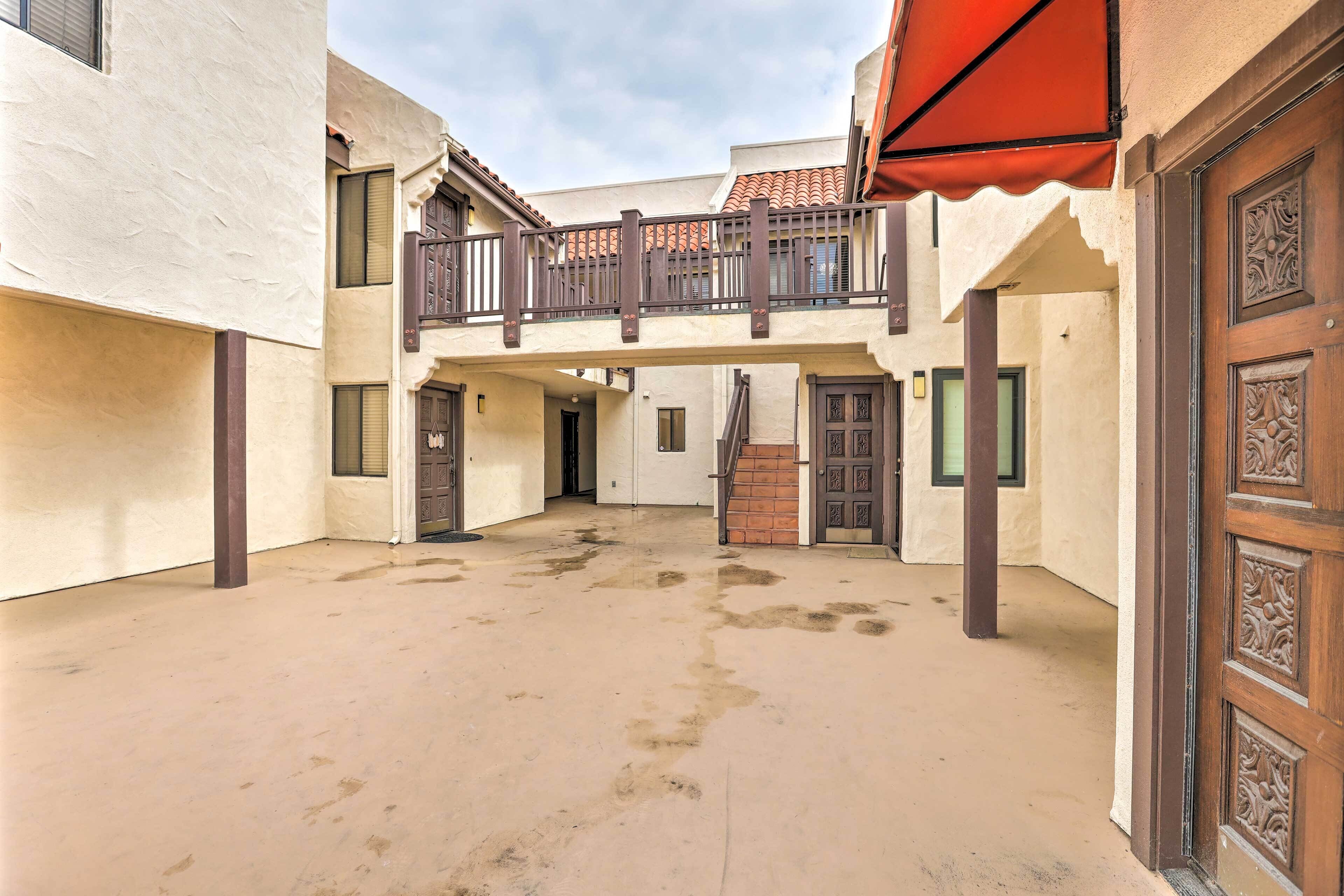 A courtyard with a covered balcony, a central door, and a covered entrance.