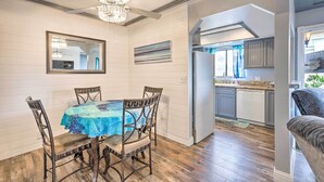 A dining area with a table covered by a blue tablecloth, surrounded by four chairs. A ceiling fan and chandelier are visible above. - Pismo Beach Condo < Walk to Beach & Wineries! (Pismo Beach)