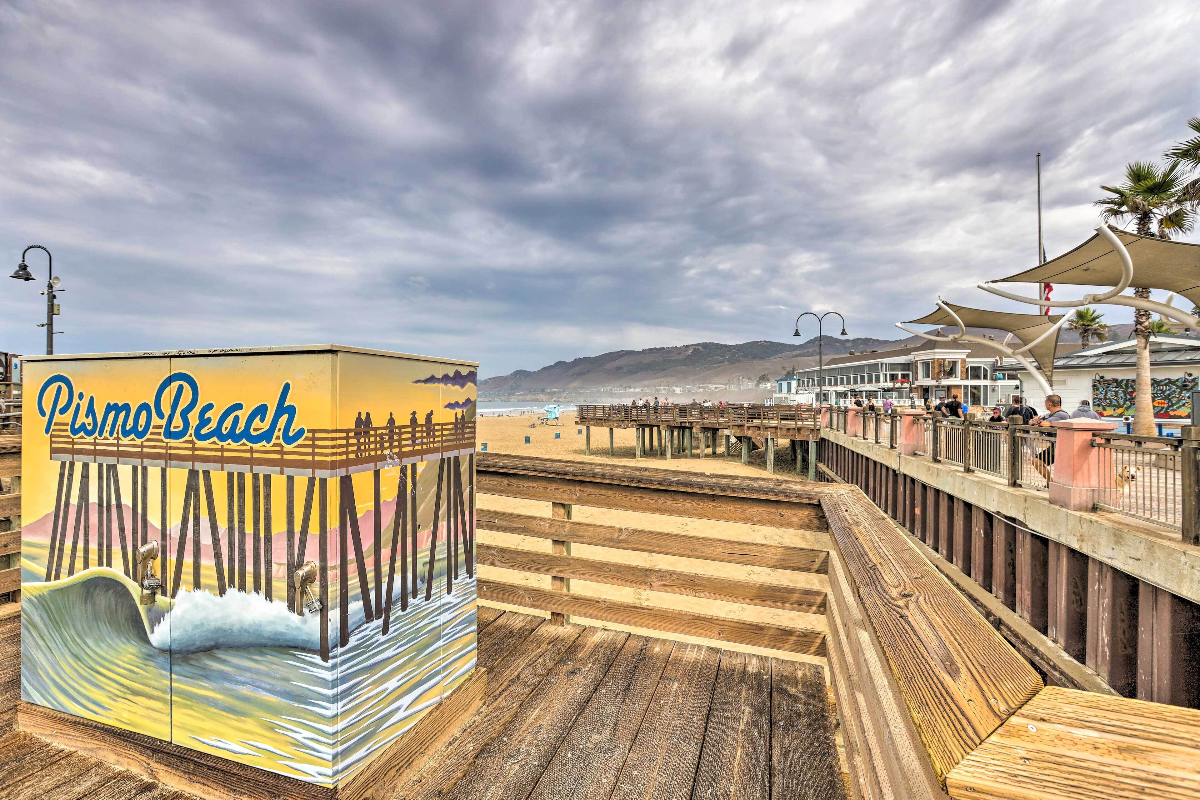 A wooden boardwalk leading to a beach with a mural of waves and mountains.