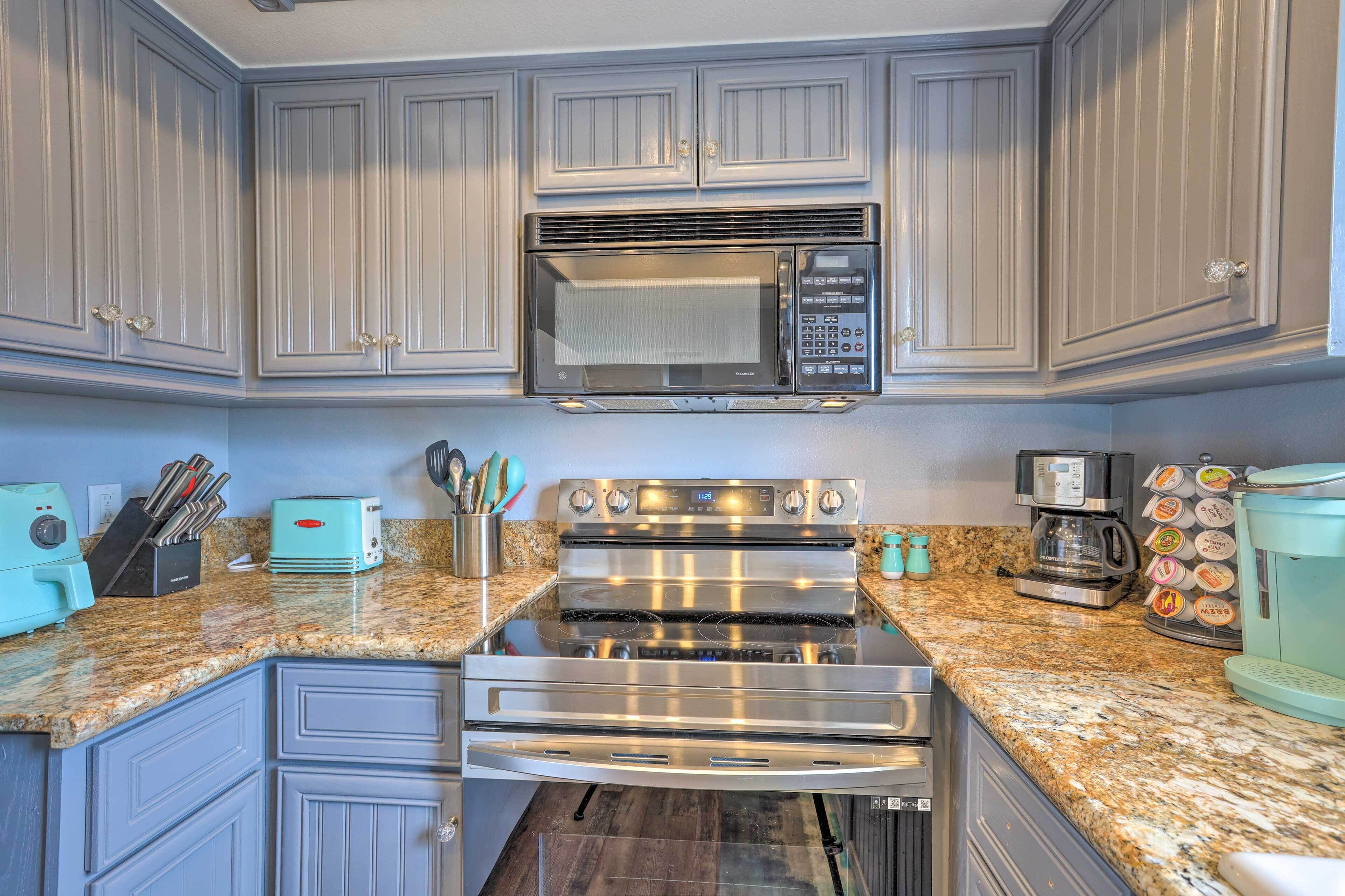 A kitchen with a stainless steel microwave, a toaster, and a coffee maker on the countertop.