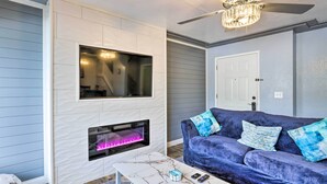 A living room with a fireplace, a ceiling fan, and a blue sofa. - Pismo Beach Condo < Walk to Beach & Wineries! (Pismo Beach)