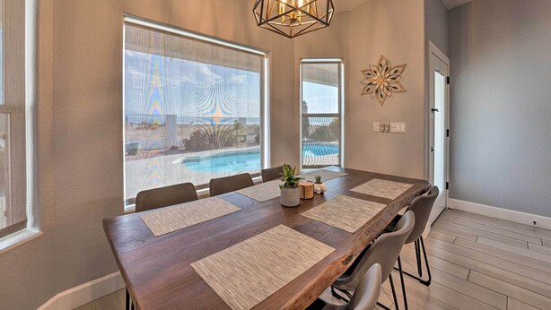 A dining area with a long table, chairs, and a view of a swimming pool. - Pool, Patio & Lake Views: Lake Havasu City Home! (Lake Havasu City)