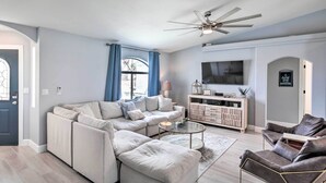 A modern living room with a sectional sofa, a glass coffee table, and a ceiling fan. - Pool, Patio & Lake Views: Lake Havasu City Home! (Lake Havasu City)