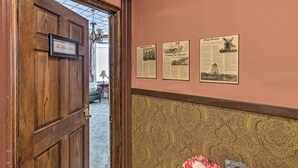 Una puerta de madera con una placa, un muro con diseño y tres documentos históricos enmarcados.