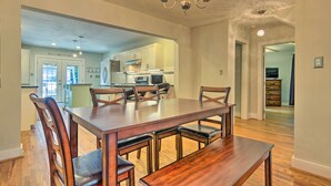 A spacious dining area with a large wooden table and chairs, a chandelier, and a view into the kitchen. - Blue Ridge Mountains Cottage w/ Pergola & Fire Pit (Hendersonville)