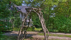 A rustic wooden arbor in a garden with a house in the background. - Blue Ridge Mountains Cottage w/ Pergola & Fire Pit (Hendersonville)