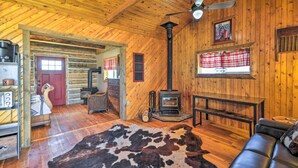 A cozy cabin interior with a wooden ceiling, a fireplace, a leather sofa, and a cowhide rug.