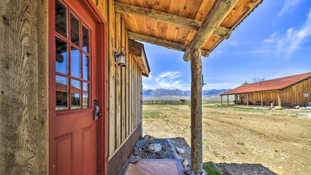 A rustic wooden building with a red door and a covered porch.