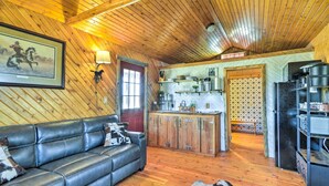 A rustic interior with a leather sofa, wooden ceiling, and a kitchen area with wooden cabinets and a refrigerator.