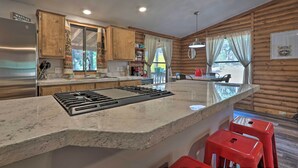 Eine Küche mit Holzwänden, einem Edelstahlkühlschrank, einer Arbeitsplatte aus Granit und roten Barhocker.