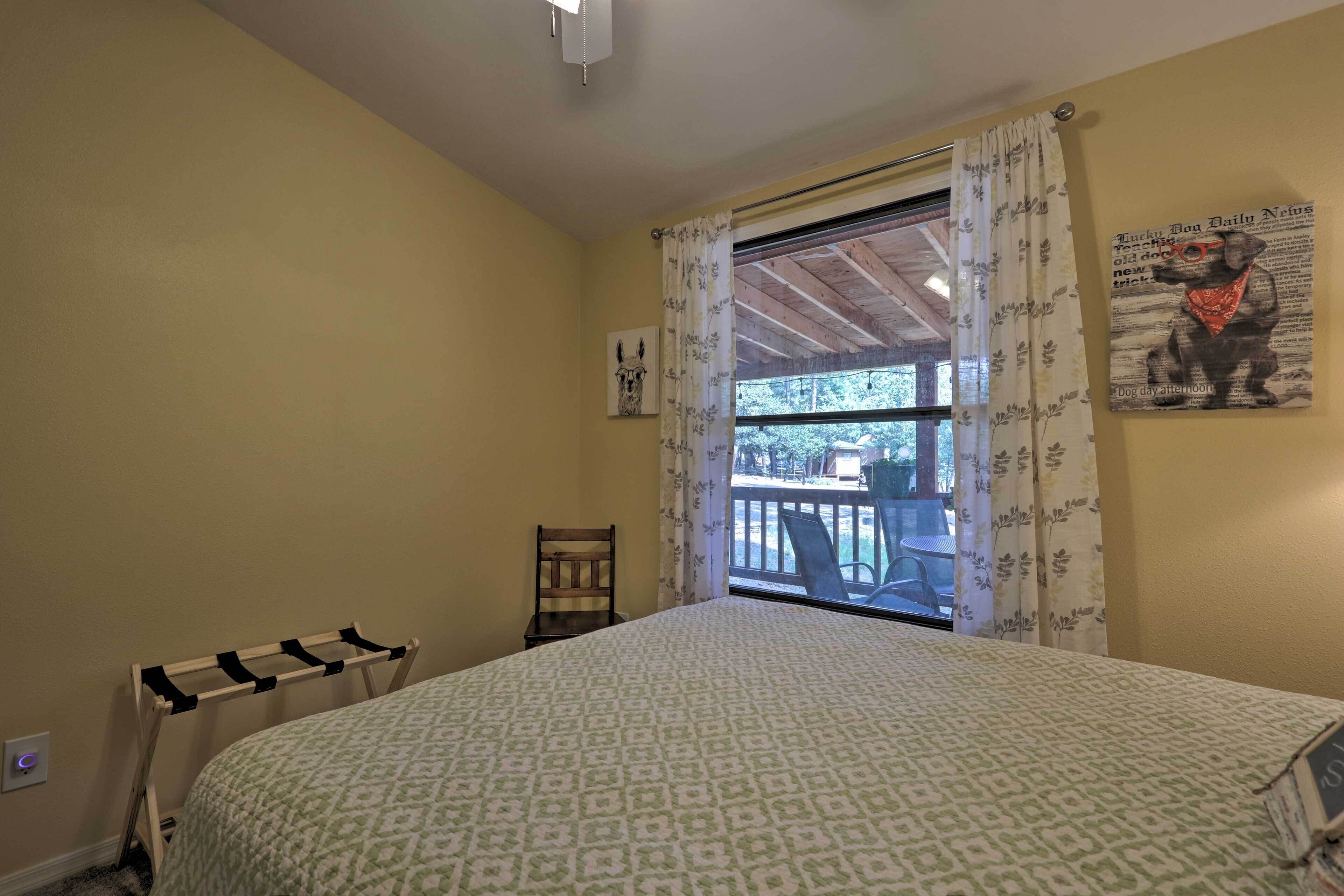 Ein Schlafzimmer mit einem Bett, einem Sessel, einem Wäscheständer, einem Fenster mit Vorhängen und einem Bild an der Wand.