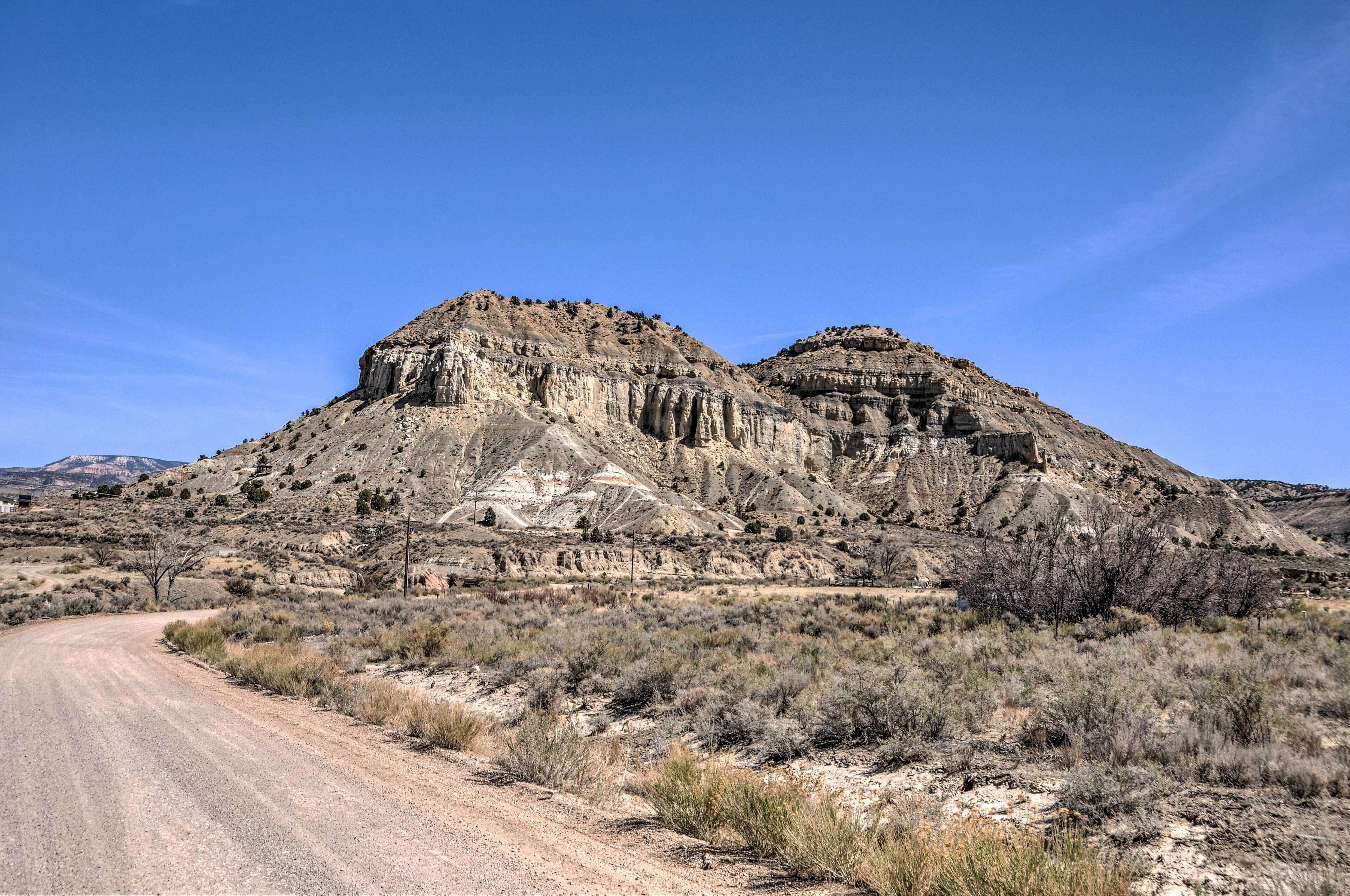 A desert landscape with a dirt road leading towards a rocky hill.