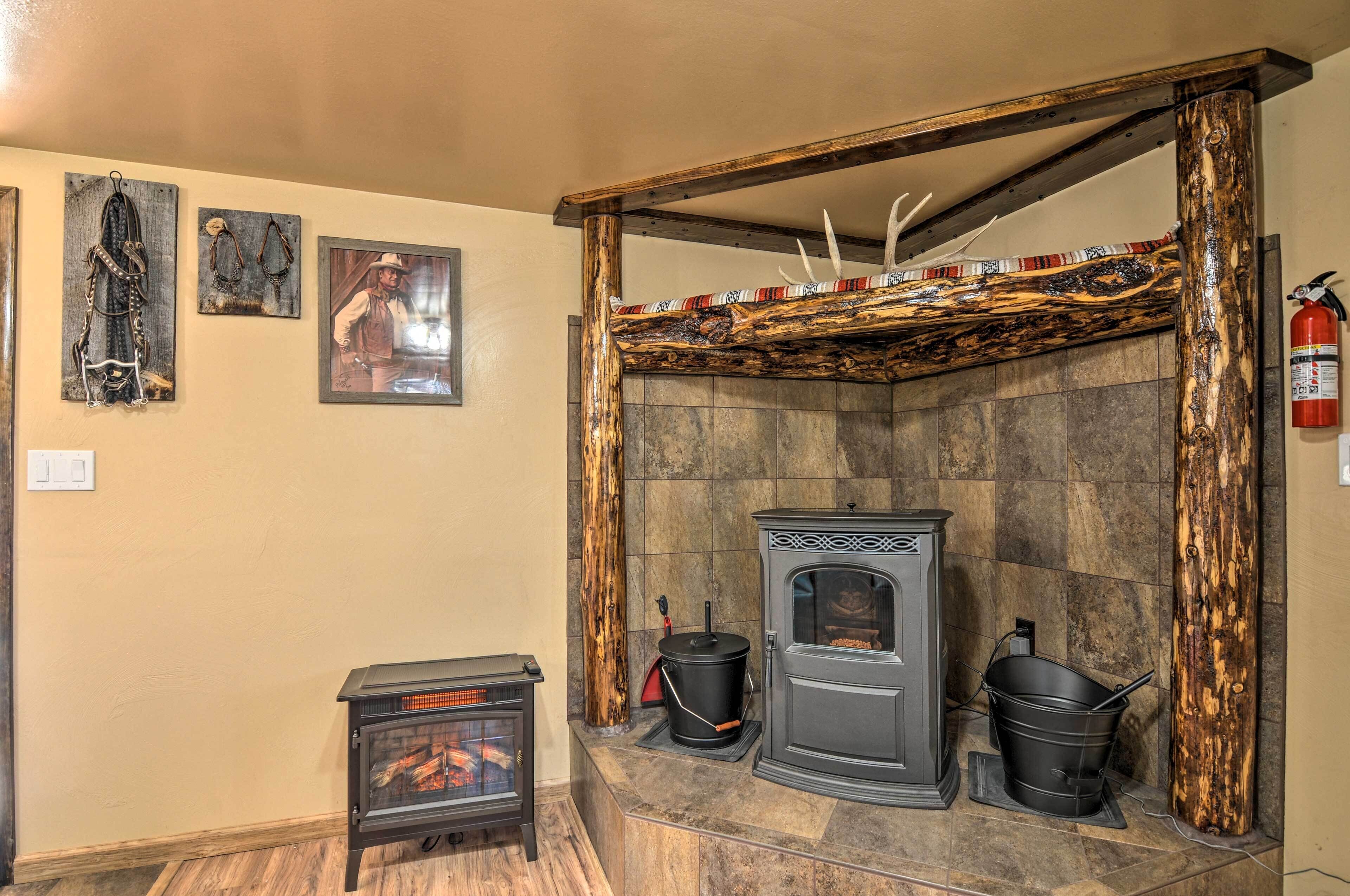 A stone fireplace with a modern wood-burning stove, a small heater, and a bucket.