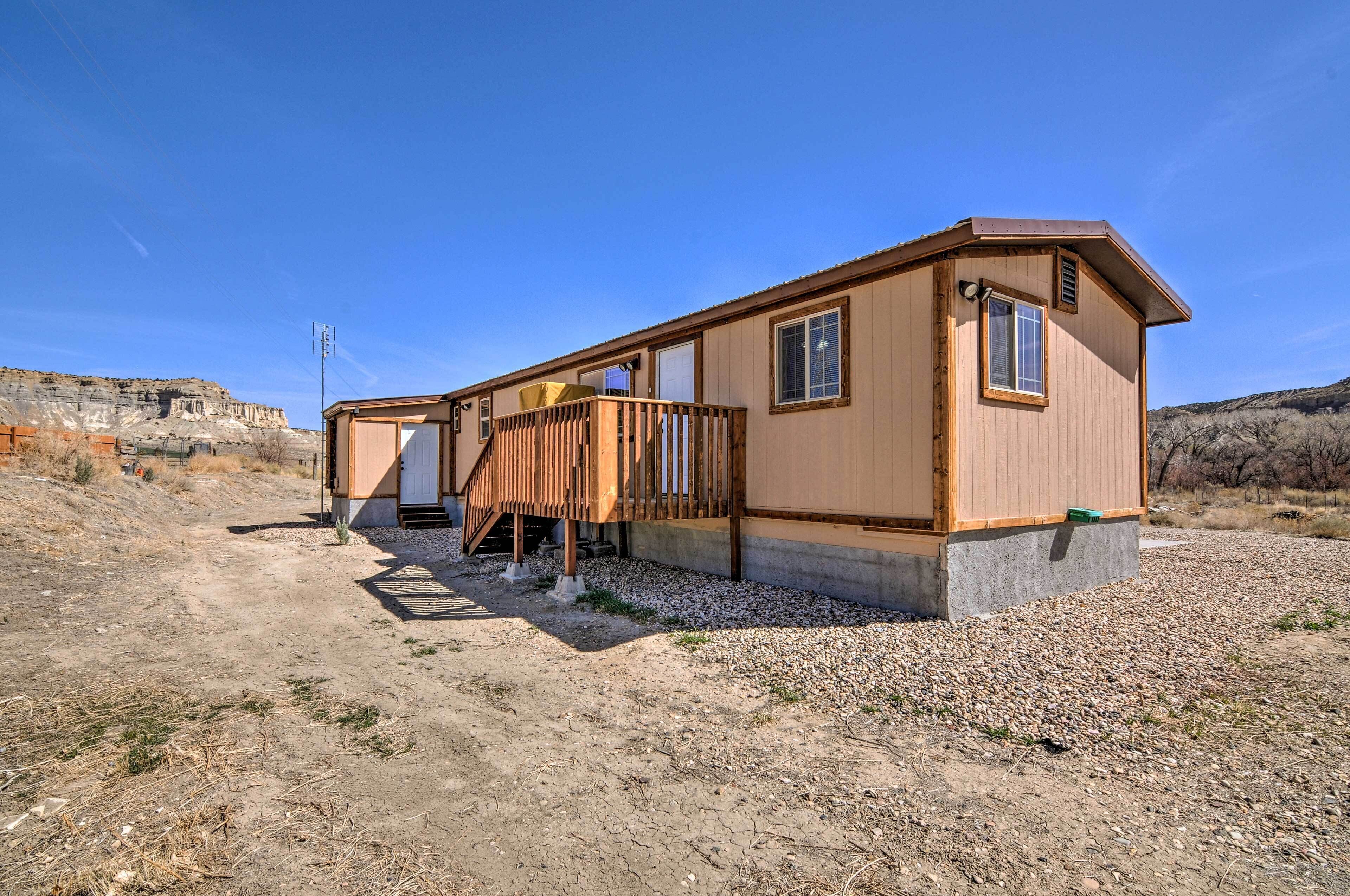 A single-story mobile home with a wooden deck, a small porch, and a concrete foundation.