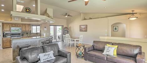 A spacious living area with a leather sofa, a coffee table, and a dining area with a white table and chairs.