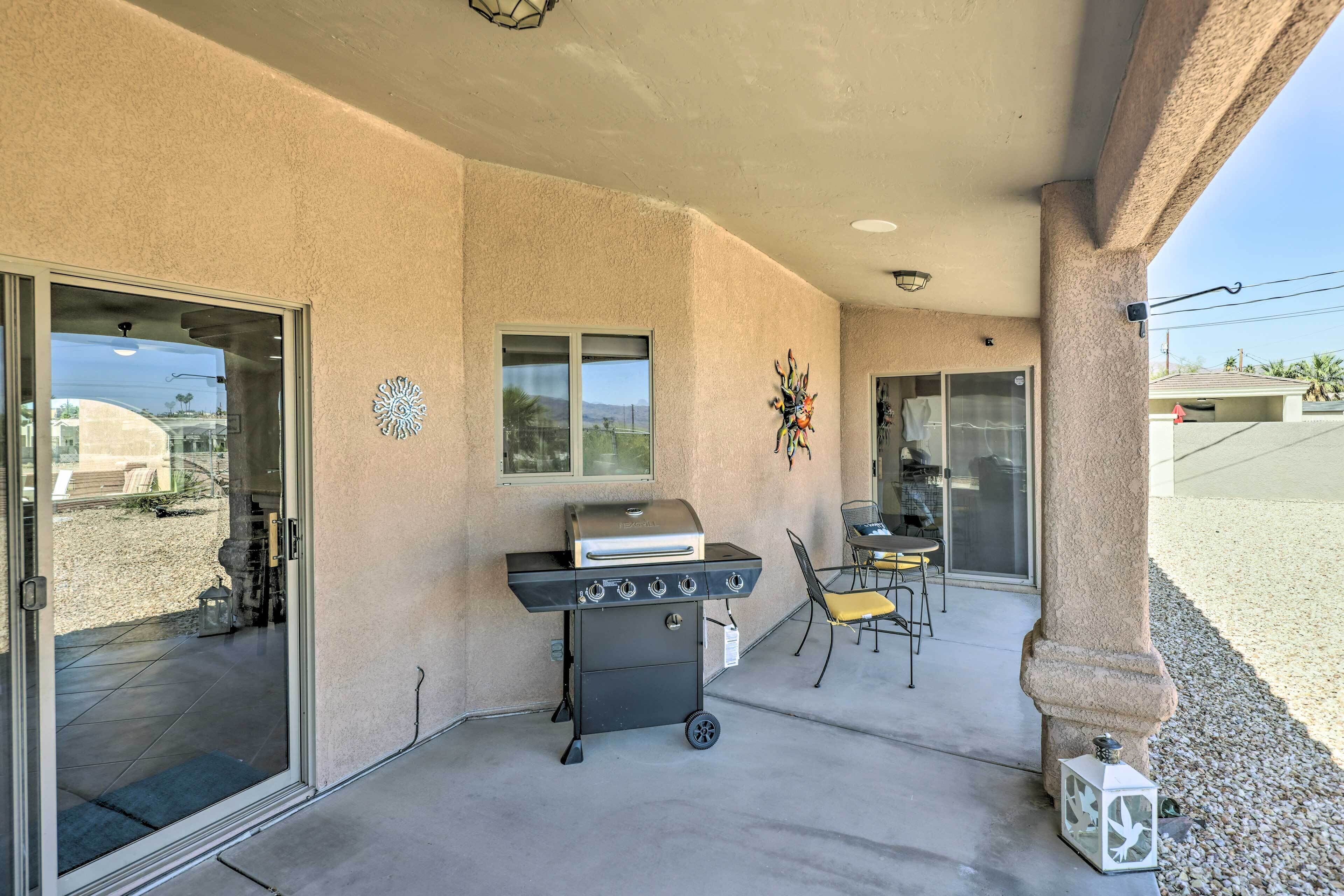An outdoor patio with a barbecue grill, sliding glass doors, and a patio chair.