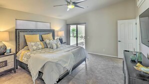 A bedroom with a bed, nightstands, a ceiling fan, a TV, and a door leading to a balcony. - 2 Mi to London Bridge: Lake Havasu Getaway (Lake Havasu City)