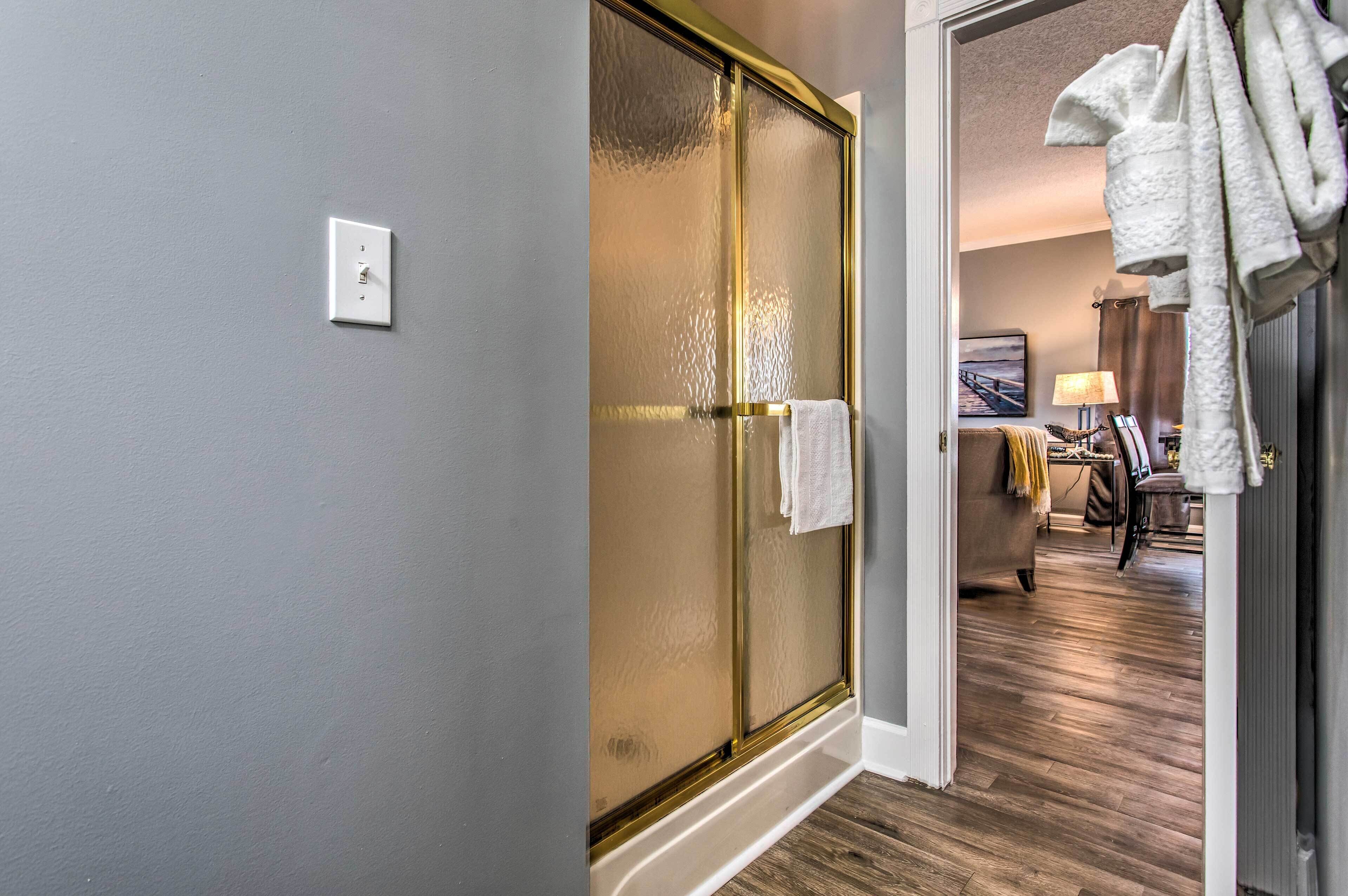A hotel room with a sliding glass door, a white towel hanging on the door, a wooden floor, and a bed with a white headboard.