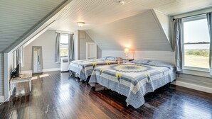 A bedroom with two beds, wooden flooring, a sloped ceiling, and a window with curtains. - Decatur Farmhouse Getaway w/ Deck & Backyard (Decatur)