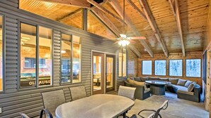 A cozy cabin interior with a dining area, seating, and large windows. - Boat Dock, Game Room: Lakefront Sunrise Beach Home (Sunrise Beach)