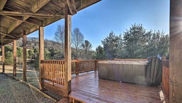A wooden deck with a hot tub, wooden railings, and a gravel path.