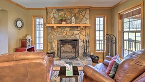 A cozy living room with a stone fireplace, leather sofas, and a clock on the wall.