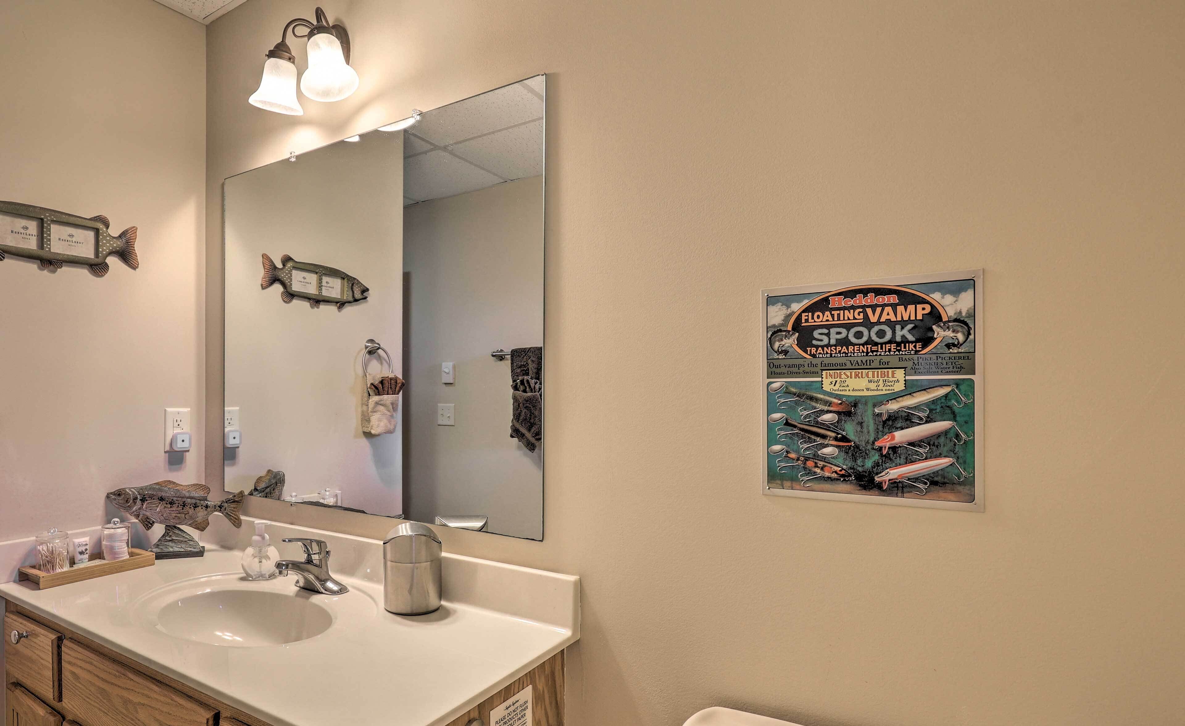 Ein Badezimmer mit großem Spiegel, Waschbecken und einem Poster, das Heddon Floating Vamp Spook bewirbt.
