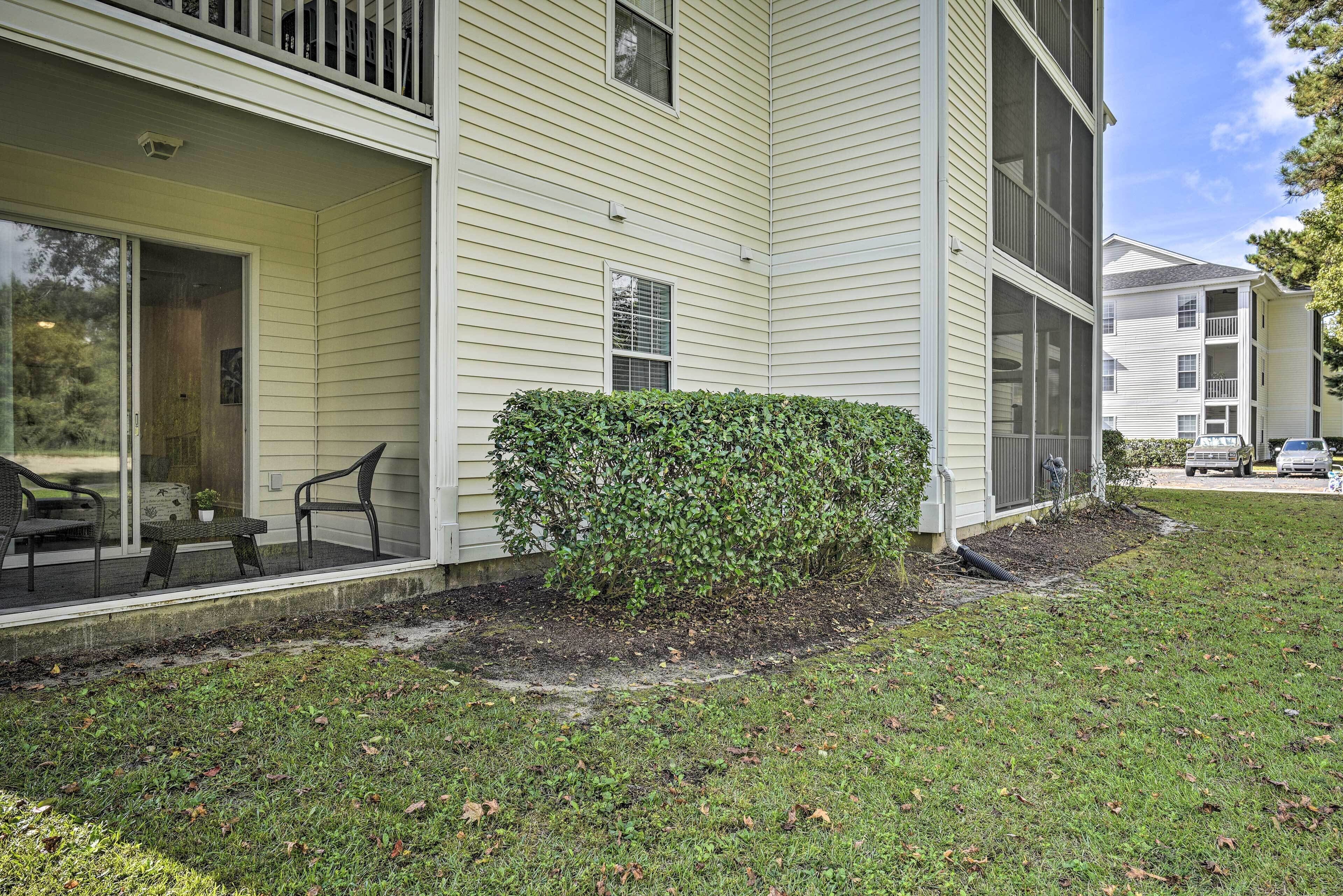 A two-story building with a covered porch, a small garden, and a car parked in the driveway.