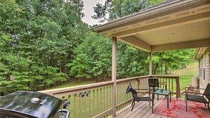 A covered deck with a grill, two chairs, and a red rug. - Bella Vista Home: Steps to Mountain Biking Trails! (Bella Vista)