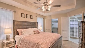 A bedroom with a wooden bed, a ceiling fan, and a nightstand with a lamp. - Bella Vista Home: Steps to Mountain Biking Trails! (Bella Vista)