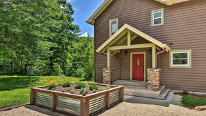 Une maison avec une porte rouge, un porche abrité et un jardin doté de plates-bandes surélevées.
