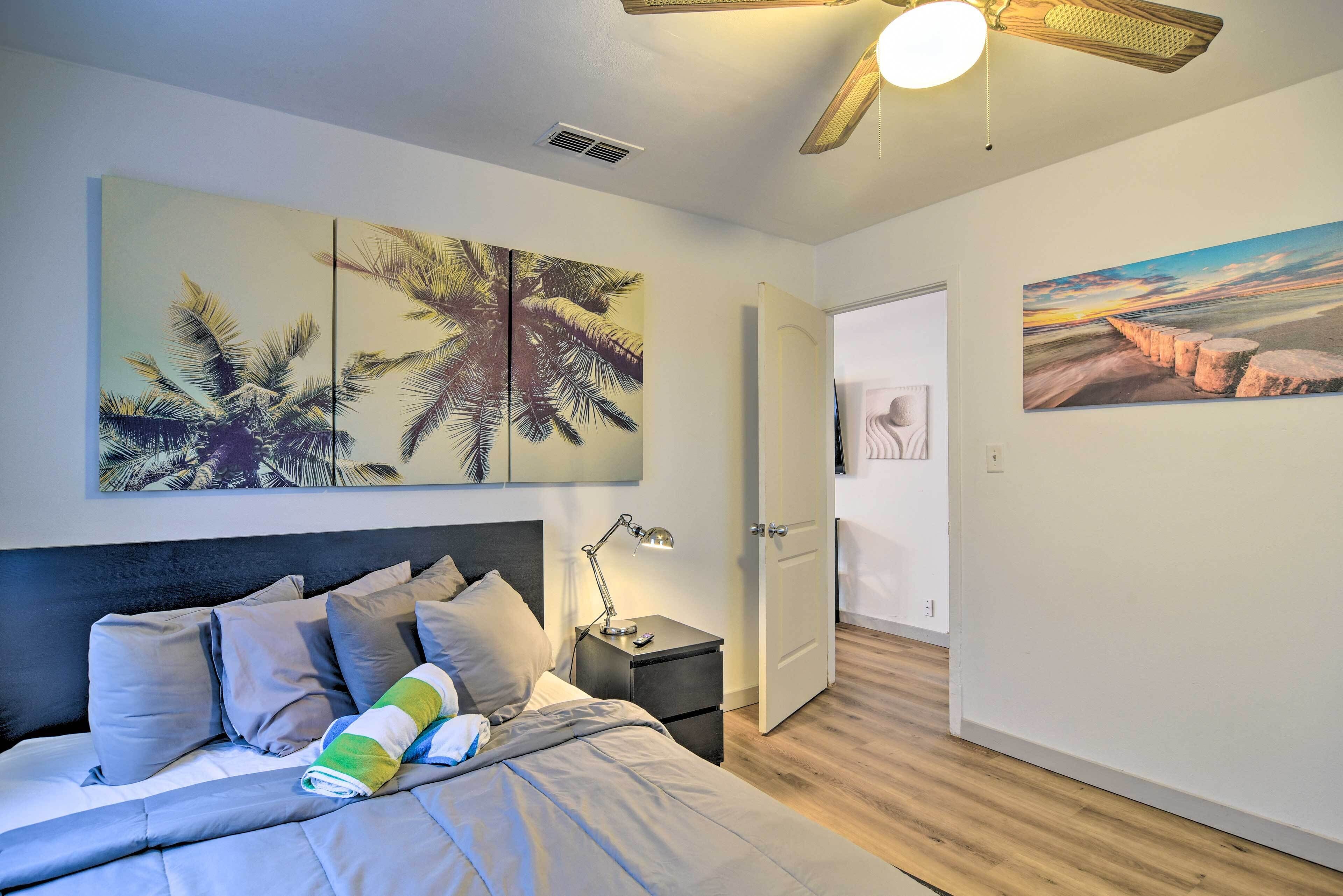 A bedroom with a bed, nightstand, and wall art.