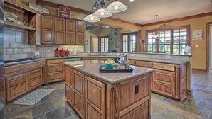 A spacious kitchen with wooden cabinets, a large island, and a stone backsplash. - Families Welcome! Lavish Celina Home w/ Game Room (Celina)